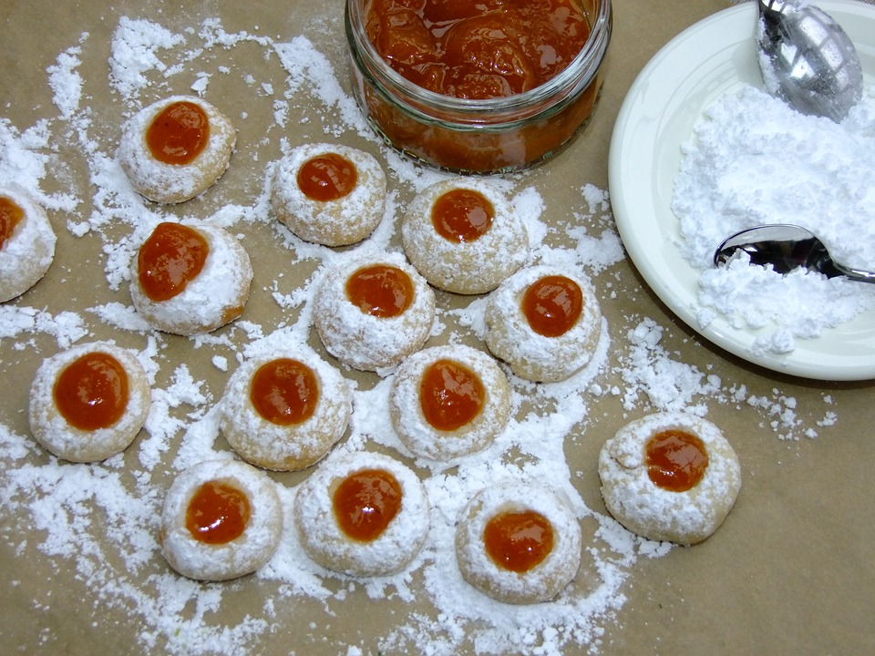 Small cookies covered with powdered sugar, and topped with blackberry jelly.