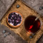 glass of blackberry tea with a bowl of blackberries besides the glass